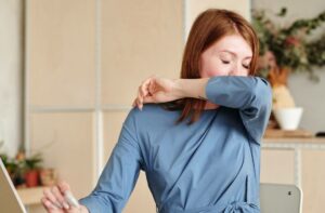 woman suffering from seasonal allergies sneezing into elbow