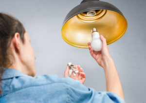 woman changing old incandescent light bulb to led energy saving lamp