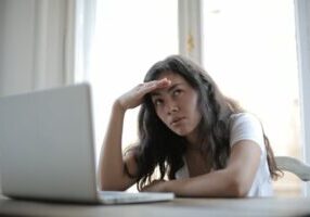 woman feeling hot in home looking at laptop