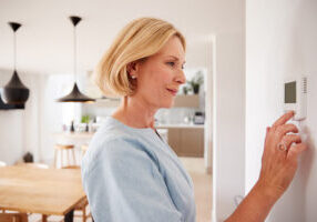 woman adjusts thermostat